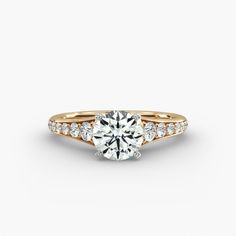 a gold engagement ring with diamonds on the band and a round cut diamond in the center