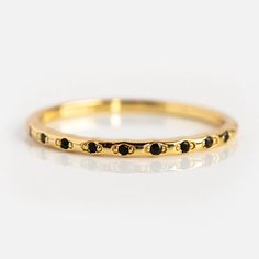 a gold ring with black stones on the inside and outside, sitting on a white surface