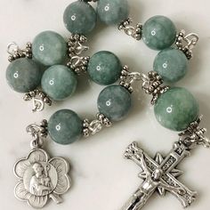 Handmade traditional Catholic single decade tenner rosary using green dyed jade smooth stone round beads. Antique silver daisy bead caps on every bead with additional leaf bead caps on Our Father bead. Antique silver shamrock shaped St. Patrick Pendant with Crosshatch Pattern Crucifix. Hail Mary beads are 8mm with the Our Father bead being 10mm. Designed to be used and/or displayed. Measures about 9.5" long. This rosary would make a beautiful gift for a baby shower, Baptism, First Communion, Confirmation, or any other special event or occasion. Comes in a beautiful black velvet pouch. I ship same or next business day. All of my rosaries are one of a kind and are my own personal creation. Photos are a part of the description-you will receive the exact rosary pictured. Please don't hesitate Silver Rosary With Round Beads For Meditation, Polished Round Beads Rosary For Jewelry Making, Adjustable Green Spiritual Rosary, Adjustable Green Rosary With Round Beads, Spiritual Round Beads Rosary For Jewelry Making, Spiritual Rosary Bracelet With Polished Beads, Green Beaded Spiritual Rosary Bracelet, Spiritual Rosary With Spacer Beads, Spiritual Rosary Bracelet With Round Beads For Jewelry Making