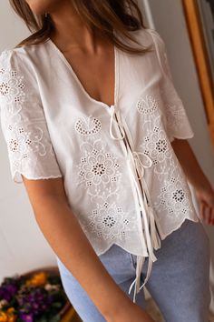 Ecru embroidered short sleeve blouse that features bows to tie in the front. This blouse offers a flowy-comfortable fit, and no lining. The perfect spring-summer wardrobe addition to style up or down! Our models also wear the Light Blue Maddie Jeans. Sizes: S-M / M-L S-M: Length 20.47 in - Width 18.90 in M-L: Length 21.26 in - Width 19.69 in 100% Cotton Handwash only Summer Tie Waist Blouse For Day Out, White Tops With Tie Sleeves For Daywear, Short Sleeve Tie Waist Tops For Daytime, White Tie Sleeves Top For Daywear, Summer Blouse With Tie Sleeves And Tie Neck, Spring Vacation Blouse With Tie Sleeves, Spring White Blouse With Tie Waist, Summer Short Sleeve Blouse With Tie Sleeves, Summer Blouse With Tie Sleeves And Short Sleeve