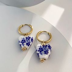 Love at first sight! You won't be able to resist these timeless heart-shaped danglers. Crafted with blue and white ceramic, these Gold Hoop earrings are perfect for cottagecore style. Get ready for your earrings to be the show-stoppers! DETAILS & SIZE Finish: 18k gold plate Material: Stainless Steel, Ceramic Measurements: Hoop Diameter: 12mm; Length: 40mm Hinged hoops with a secure snap post closure Shop Earrings for more options! Porcelain Earrings, Ceramic Teapot, Cottagecore Style, Ceramic Teapots, New Trend, White Heart, Stainless Steel Earrings, Heart Beads, Gold Hoops