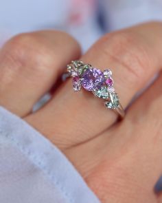 a woman's hand holding a ring with three different colored stones