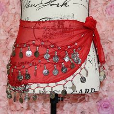 a mannequin is adorned with red fabric and lots of silver jewelry on it