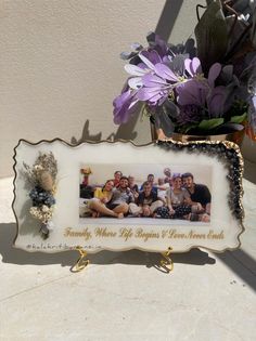 a family photo frame sitting on top of a table next to a vase filled with flowers