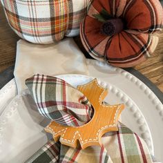 two plaid pumpkins sitting on top of a white plate next to other fall decorations