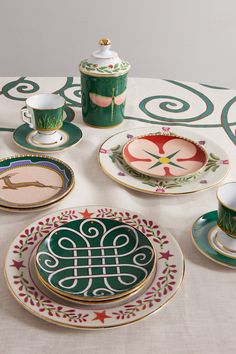 a table topped with plates and cups filled with saucers on top of a white table cloth