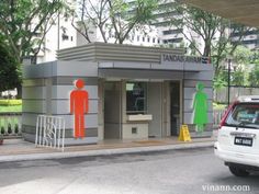 a car is parked in front of a small building with orange and green figures on it