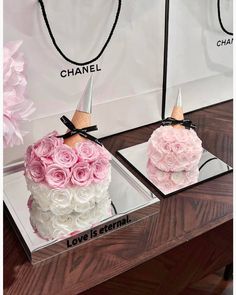 two cakes decorated with pink and white roses are on display in front of a mirror