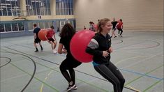 two girls playing with red and blue balls in an indoor gym