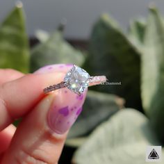 a woman's hand holding an engagement ring with a diamond on the top and side