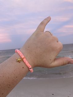 It is a pink and orange clay bead bracelet that has a gold star fish charm on the front. Pink Starfish Charm Jewelry, Pink Beaded Bracelets With Star Charm, Adjustable Pink Beaded Bracelets With Star Charm, Adjustable Pink Beaded Bracelet With Star Charm, Preppy Accessories, Clay Bead Bracelet, Bracelet Quotes, Bracelets Design, Clay Bracelet