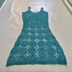 a blue crocheted dress laying on top of a bed