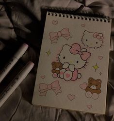 a notebook with hello kitty and teddy bears on it next to two crayons