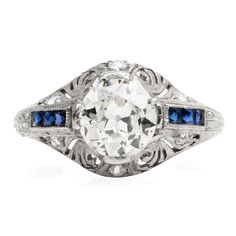 an antique diamond and blue sapphire ring with filigrees on the sides, in white gold