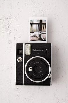 an old fashioned camera sitting on top of a wooden table next to a white wall