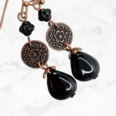 Perfect black dangle brass in copper. Richly detailed copper Mandala flower discs suspend Czech glass teardrop beads.  These earrings go with everything from jeans to a little black dress. A wardrobe must-have! Hypoallergenic ear wires (nickel and lead free). Choose ear wire style at checkout.  Free gift packaging included. Earrings are carded and in an organza gift bag. Artisan glass beads produced in small quantities in the Czech Republic Available in ANTIQUE SILVER finish here: https://www.et Black Bohemian Teardrop Dangle Earrings, Handmade Black Bohemian Teardrop Earrings, Elegant Copper Teardrop Earrings, Black Bohemian Teardrop Earrings For Gift, Bronze Metal Dangle Teardrop Earrings, Black Bohemian Teardrop Earrings As Gift, Bohemian Black Teardrop Earrings As Gift, Bronze Metal Teardrop Dangle Earrings, Bronze Metal Teardrop Earrings