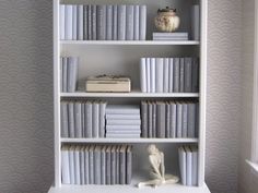 a white book shelf with books and figurines on it