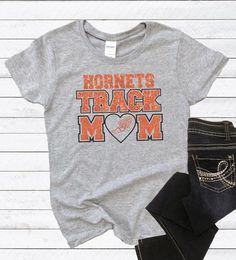 Track Mom T-Shirt, Track and Field, Track Mom Tee, Track Mom Gift, Sports Mom T-Shirt Game Day Athletic Heather Short Sleeve T-shirt, Pre-shrunk Heather Grey T-shirt For Fan Merchandise, Athletic Heather Short Sleeve Fan Apparel T-shirt, Casual T-shirt With Heat Transfer Vinyl For Sports Events, Athletic Heather Cotton T-shirt For Fans, Athletic Heather Graphic Tee For Sports Events, Athletic Heather Short Sleeve T-shirt Fan Apparel, Heather Grey Letter Print T-shirt For Fans, Athletic Heather Short Sleeve T-shirt For Fans