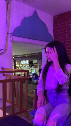 a woman sitting on a chair talking on her cell phone in a purple lit room