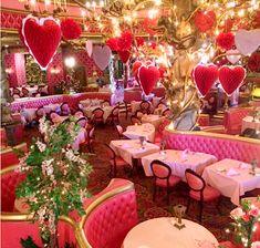 the interior of a fancy restaurant decorated in pink and gold with hearts hanging from the ceiling