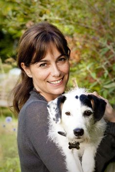 a woman holding a white and black dog in her arms