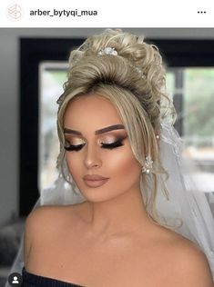 a woman with blonde hair wearing a wedding veil and makeup looks at the camera while standing in front of a window