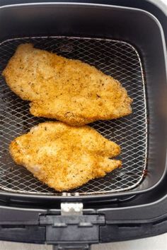 two pieces of chicken cooking in an air fryer