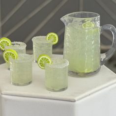 pitcher and glasses filled with lemonade on top of a white table