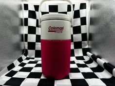 a red and white cooler sitting on top of a black and white checkered floor