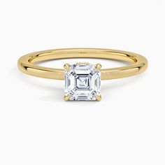 a yellow gold ring with an emerald cut diamond