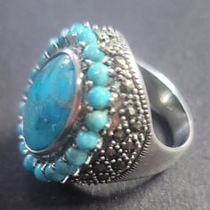 R230. $99 Turquoise And Marcasite Cocktail Ring Size 7. Big, Bold Beautiful! Do You Dare? Oval Sleeping Beauty Turquoise And Marcasite Ring .925 Sterling Silver. Est Retail $386. Never Worn. Made In Thailand. Size 7. The Bright Blue Hue Of The Main Stone, Along With A Halo Of 20 Smaller Round Turquoise Stones, Enhanced By Rows Of Diamond Cut Marcasite 925 Sterling Silver Weighs 11.5grams. All Weights And Measurements Are Approximate. Round Turquoise Ring With Gemstone Accents, Elegant Oval Nickel-free Turquoise Ring, Elegant Oval Turquoise Ring Nickel Free, Blue Turquoise Ring With Sterling Silver, Blue Turquoise Sterling Silver Ring With Stones, Elegant Silver Turquoise Ring With Gemstone Accents, Bohemian Blue Turquoise Ring With Stones, Marcasite Ring, Sleeping Beauty Turquoise