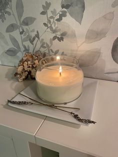 a lit candle sitting on top of a white table