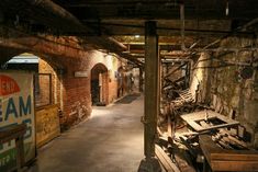 an alley way with old furniture and signs on the walls, in front of a brick wall