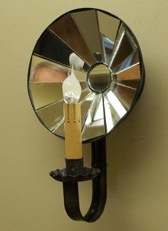 a mirror mounted to the side of a wall next to a candle holder with a fan on it