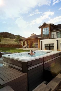 a woman sitting in a large hot tub next to a house on a sunny day