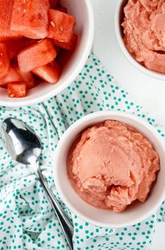 three bowls filled with watermelon ice cream next to spoons on a table