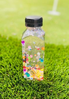 a bottle filled with gummy bears sitting on top of green grass