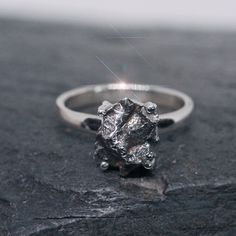 This ring is made from beautiful genuine Campo del Cielo Meteorite, and is size 6.  The Campo del Cielo refers to a group of iron meteorites or to the area where they were found situated on the border between the provinces of Chaco and Santiago del Estero, 620 miles northwest of Buenos Aires, Argentina. The crater field covers an area of 3×20 kilometers and contains at least 26 craters, the largest being 115×91 meters. The craters' age is estimated at 4,000-5,000 years.  The craters, containing iron masses, were reported in 1576 but were already well known to the aboriginal inhabitants of the area. The craters and the area around contain numerous fragments of an iron meteorite. The total weight of the pieces so far recovered exceeds 100 tons, making the meteorite the heaviest one ever reco Raw Stone Promise Ring, Round Raw Stone Promise Rings, Silver Rings With Raw Stone, Minimalist Silver Ring With Raw Stone, Silver Promise Ring With Raw Stone, Silver Rings With Raw Stone For Promise, Silver Raw Stone Anniversary Ring, Silver Anniversary Ring With Raw Stone, Silver Raw Stone Ring For Anniversary