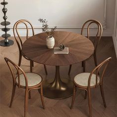 a wooden table with four chairs around it and a vase on top of the table