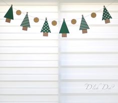 paper christmas trees are hanging on the clothesline in front of white shutters with polka dots