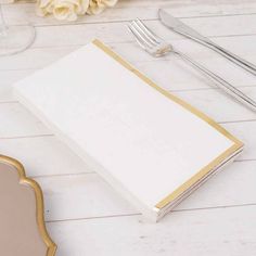 an empty menu sitting on top of a table next to utensils and flowers