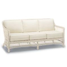 a white wicker couch sitting on top of a white floor