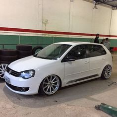 a white car parked in a garage next to some black and red tire rims