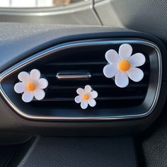 two white flowers are placed on the center console of a car's dash board