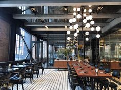 an empty restaurant with black and white checkered flooring, chandelier hanging from the ceiling