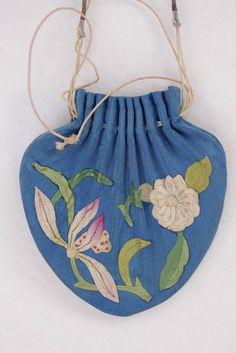 a blue purse with flowers painted on the front and side, hanging from a string