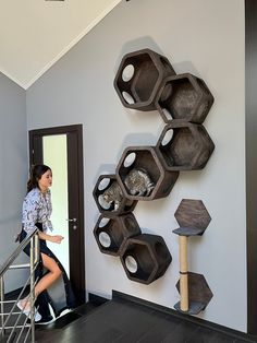 a woman is walking up the stairs in front of a wall with hexagonal shelves