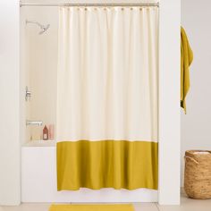 a yellow and white shower curtain next to a bath tub with a towel on it