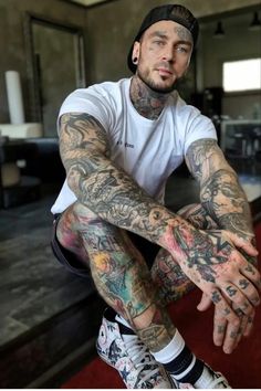 a man with tattoos sitting on the ground