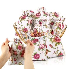 a woman's hand is holding two bags with flowers on them and the bag has gold handles